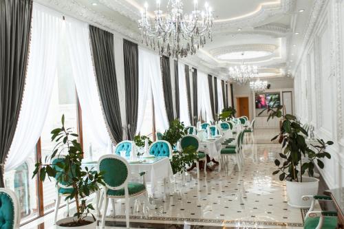 une salle à manger avec des tables blanches et des chaises bleues dans l'établissement Konstantin Plaza, à Samarcande