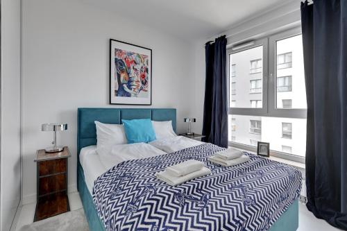 - une chambre avec un lit bleu et blanc et une fenêtre dans l'établissement Gdańsk Comfort Apartments Bastion Wałowa, à Gdańsk