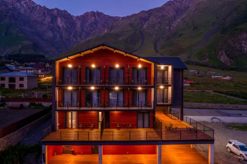 uma casa com um deque com montanhas ao fundo em Hotel Darchi Kazbegi em Kazbegi