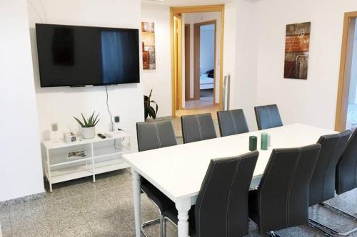 einen Konferenzraum mit einem Tisch und Stühlen sowie einem Flachbild-TV in der Unterkunft Ferienwohnung mit fantastischem Ausblick & SmartTv in Waldstetten