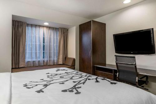 a hotel room with a bed and a flat screen tv at Sleep Inn & Suites in Kalamazoo