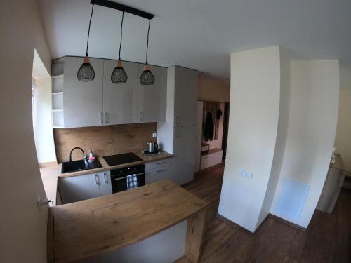 a kitchen with white cabinets and a wooden counter top at Apartamentai Rusnės centre in Rusnė