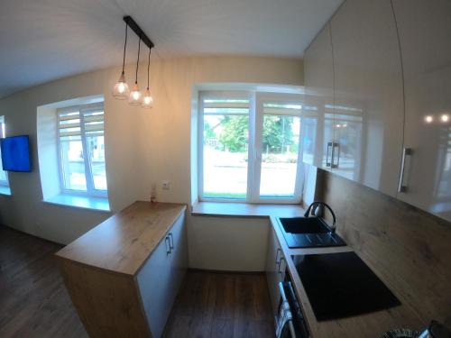 a kitchen with a wooden counter top and two windows at Apartamentai Rusnės centre in Rusnė