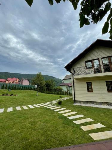 a house with a grass yard next to a building at Cottage Zelman in Yaremche