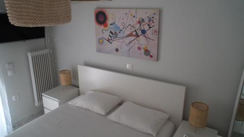 een slaapkamer met een wit bed en een schilderij aan de muur bij Lovely apt near the beach in Athene