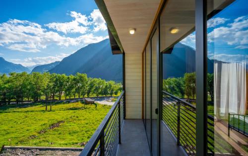 a house with a balcony with a view of mountains at Hotel Darchi Kazbegi in Stepantsminda