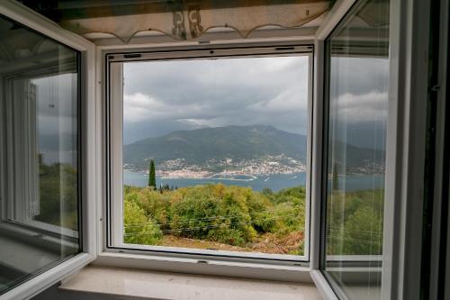 a window with a view of a city and the water at Apartments Mitrovic in Lustica