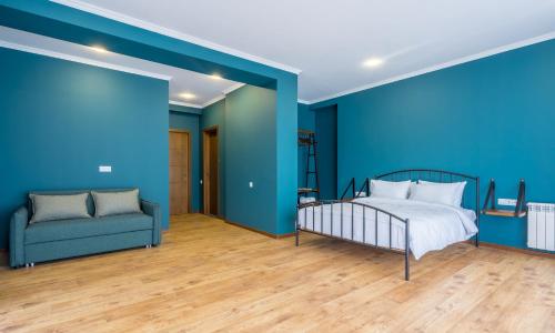 a bedroom with blue walls and a bed and a couch at Hotel Darchi Kazbegi in Stepantsminda