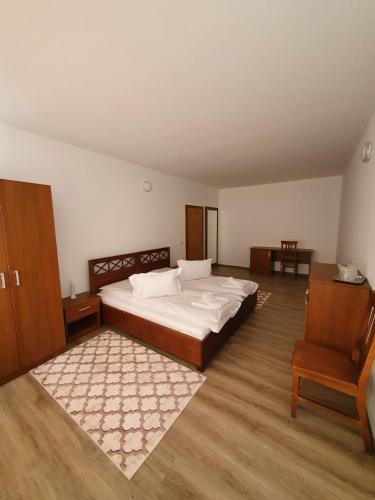 a bedroom with a large bed and a chair at Pensiune Restaurant Cosna in Coşna