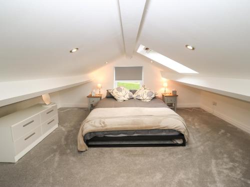 a large attic bedroom with a bed and a window at The Wheel House in Stalybridge