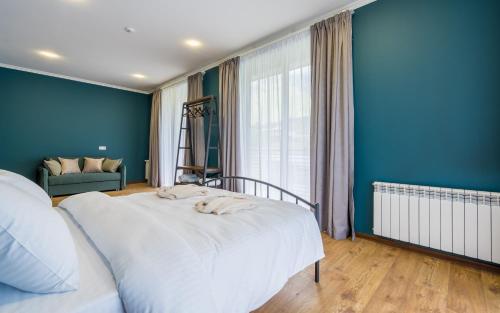 a bedroom with a white bed and a blue wall at Hotel Darchi Kazbegi in Stepantsminda