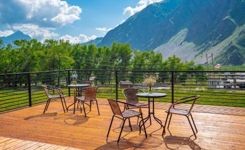 a table and chairs on a deck with a view of mountains at Hotel Darchi Kazbegi in Stepantsminda