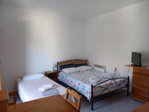 a bedroom with two beds and a table and a tv at Apartment Kasperakos in Skiathos Town