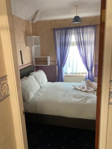 a bedroom with a bed with blue curtains and a window at 'Melrose' at stayBOOM in Lancaster