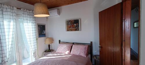 Un dormitorio con una cama con almohadas rosas y una ventana en House in Zaloggo en Preveza