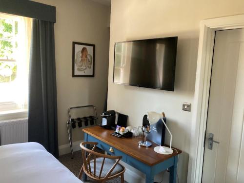 a room with a desk with a bed and a television at Downs Hotel in Stanmer