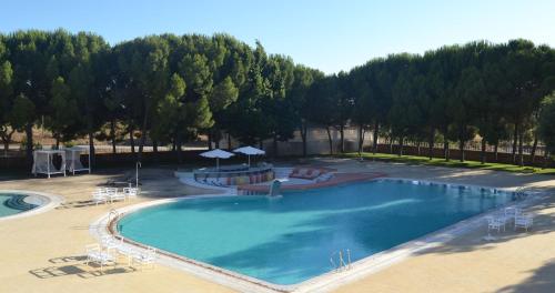 an overhead view of a large swimming pool with chairs and umbrellas at Hotel Campo do Rosmaninho in Castelo Branco