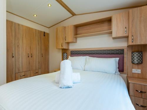 Cama blanca grande en habitación con armarios de madera en Pass the Keys Delightful 2 bedroom caravan with parking, en Wimborne Minster