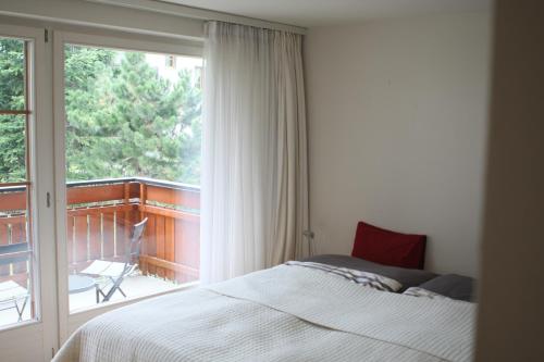 a bedroom with a bed and a balcony with a window at Zermatt La Vallée in Zermatt