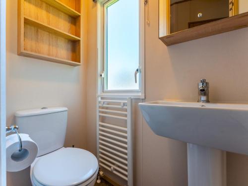 baño con aseo y lavabo y ventana en Pass the Keys Delightful 2 bedroom caravan with parking, en Wimborne Minster