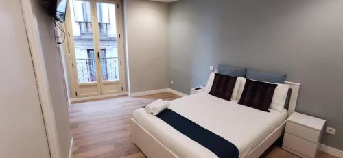 ein Schlafzimmer mit einem weißen Bett und einem Fenster in der Unterkunft Apartamentos Sol Madrid in Madrid