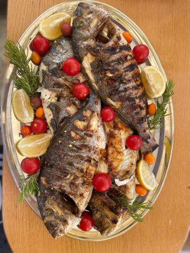 a plate of fish and vegetables on a table at Apartman OZANA in Blace