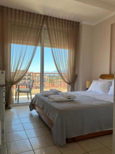 a bedroom with a bed and a large window at Blue Jasmine in Aigio