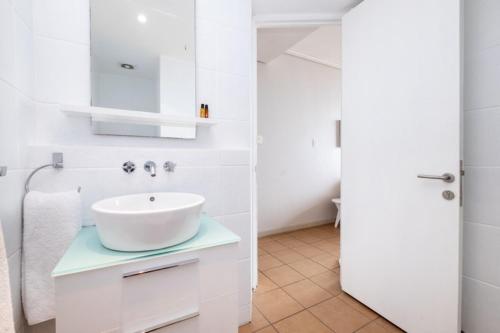 een witte badkamer met een wastafel en een spiegel bij Durban Point Waterfront, 805 Quayside 40 Canalquay Rd in Durban