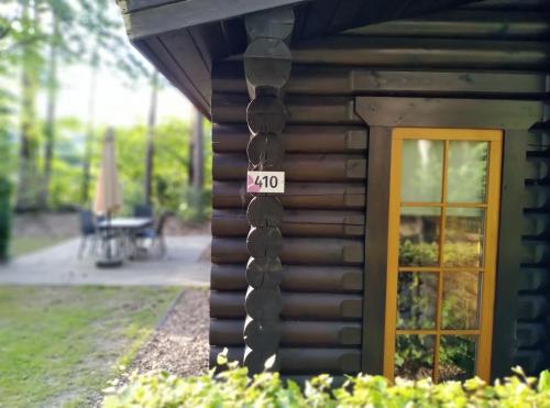 a log cabin with a door and a sign on it at De Stamper - De Wije Werelt in Otterlo