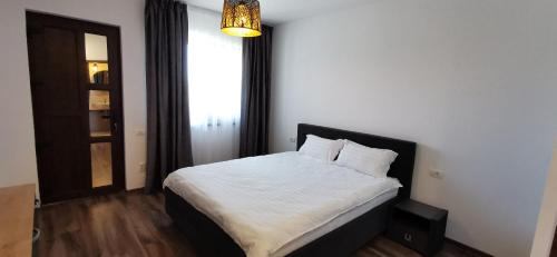 a bedroom with a bed with white sheets and a window at Bobocel in Sfântu Gheorghe