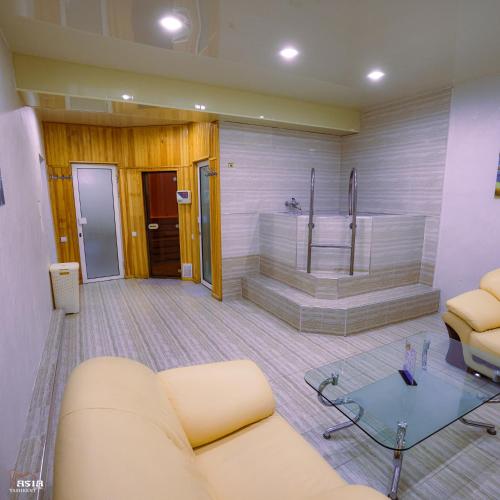 een woonkamer met een bad, een bank en een tafel bij Asia Tashkent Hotel in Tasjkent