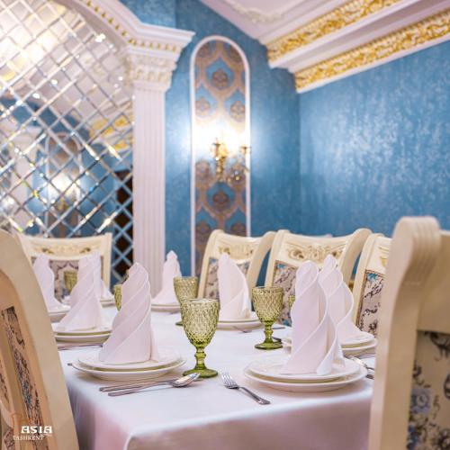 タシュケントにあるAsia Tashkent Hotelの青い壁と白いナプキンが置かれたテーブルのあるダイニングルーム