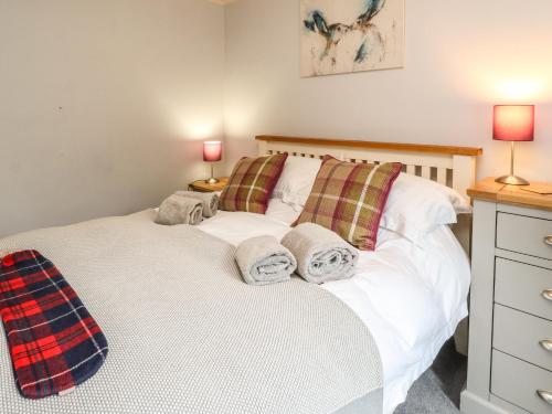 um quarto com uma cama branca e 2 almofadas em Puidrac Cottage em Lochearnhead