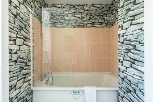 a bathroom with a bath tub and a stone wall at Family House in Disneyland BMYGUEST in Serris