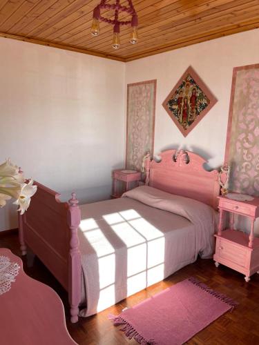 a bedroom with a pink bed and two tables at Avó da Rosa in Ribeira Quente