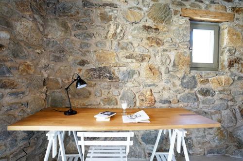 a stone wall with a wooden table with a lamp at Tortuga house 180 sea view - Serifians Residences in Serifos Chora
