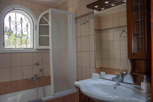 een badkamer met een wastafel, een bad en een raam bij Emmy villa paleokastritsa in Paleokastritsa