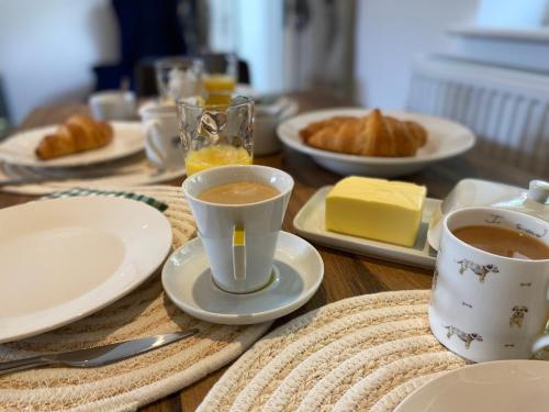 a wooden table with two cups of coffee and croissants at Burgess Yard 2-bedroom cottage, Bath in Bath