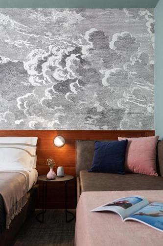 a bedroom with two beds and a painting of clouds at Hotel Tremoggia in Chiesa in Valmalenco