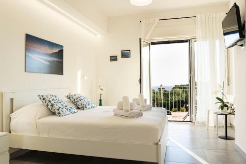 ein weißes Schlafzimmer mit einem Bett und einem großen Fenster in der Unterkunft Sulla Valle in Agrigento