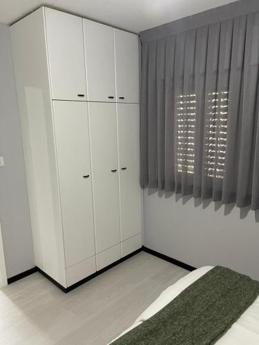 a bedroom with white cabinets and a bed and a window at Menachem's Apartment in Bet Sheʼan