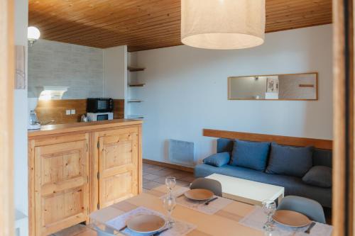 a living room with a table and a blue couch at Résidence Sunêlia Les Logis d'Orres in Les Orres