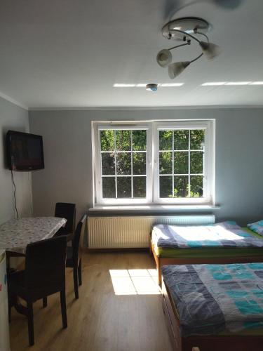 a room with two beds and a table and a window at Pokoje Gdynia Demptowo in Gdynia