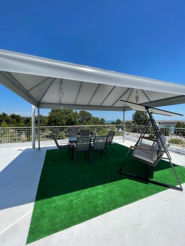 a white pavilion with chairs and tables on a green rug at Hotel Medousa in Skála Alykís