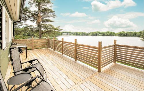 a wooden deck with chairs and a view of a lake at Amazing Home In Örkelljunga With Sauna in Orkelljunga