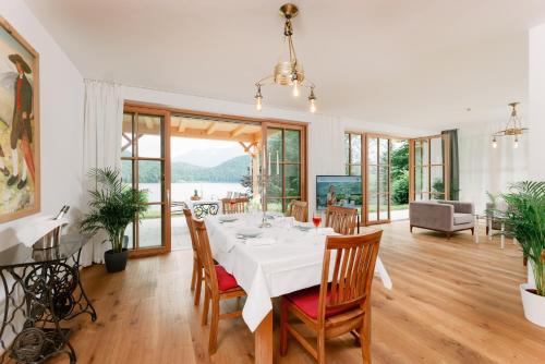 a dining room with a white table and chairs at Villa Frischmuth am See in Altaussee