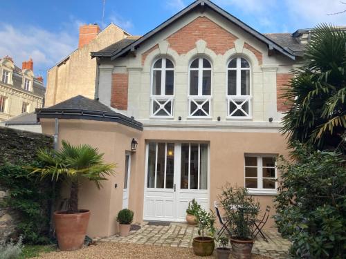 une maison avec une porte blanche et quelques plantes dans l'établissement La Maison du Cocher - Studio climatisé en Hypercentre, à Angers