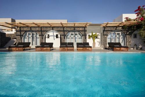 une piscine avec des chaises longues et une piscine dans l'établissement Kalisti Hotel & Suites, à Fira