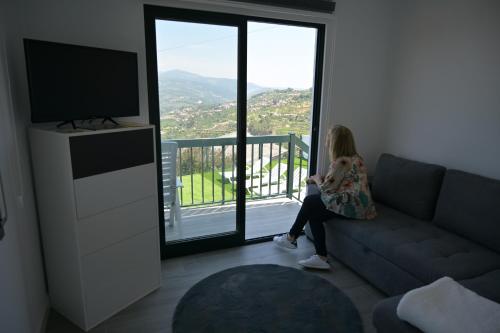 a young girl sitting on a couch looking out a window at Casa da Costa Resende in Cárquere