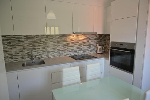 a white kitchen with a sink and a stove at Casa da Costa Resende in Cárquere